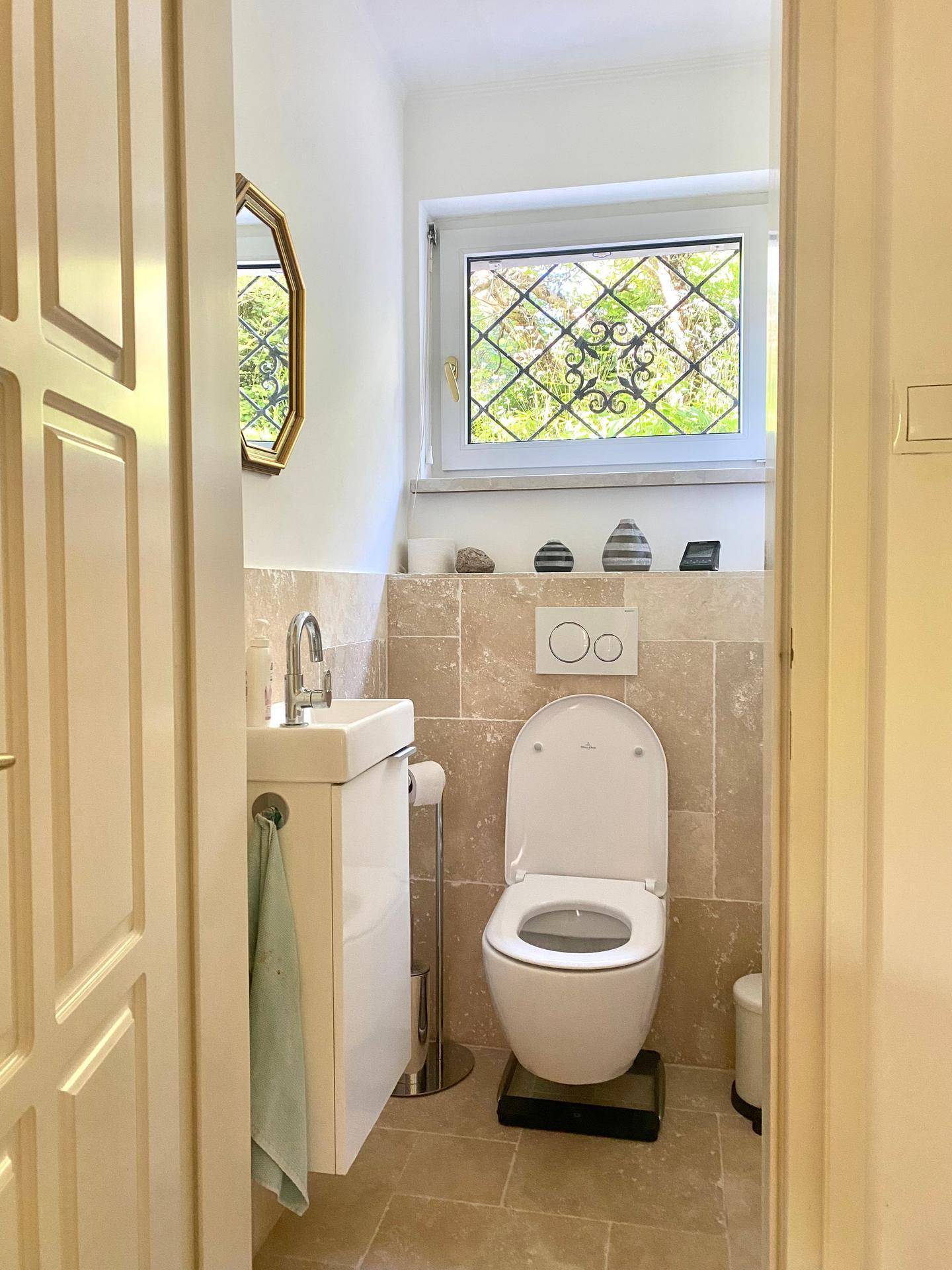 Modernes Gäste-WC mit wandhängender Toilette, kleinem Waschbecken und Fenster.