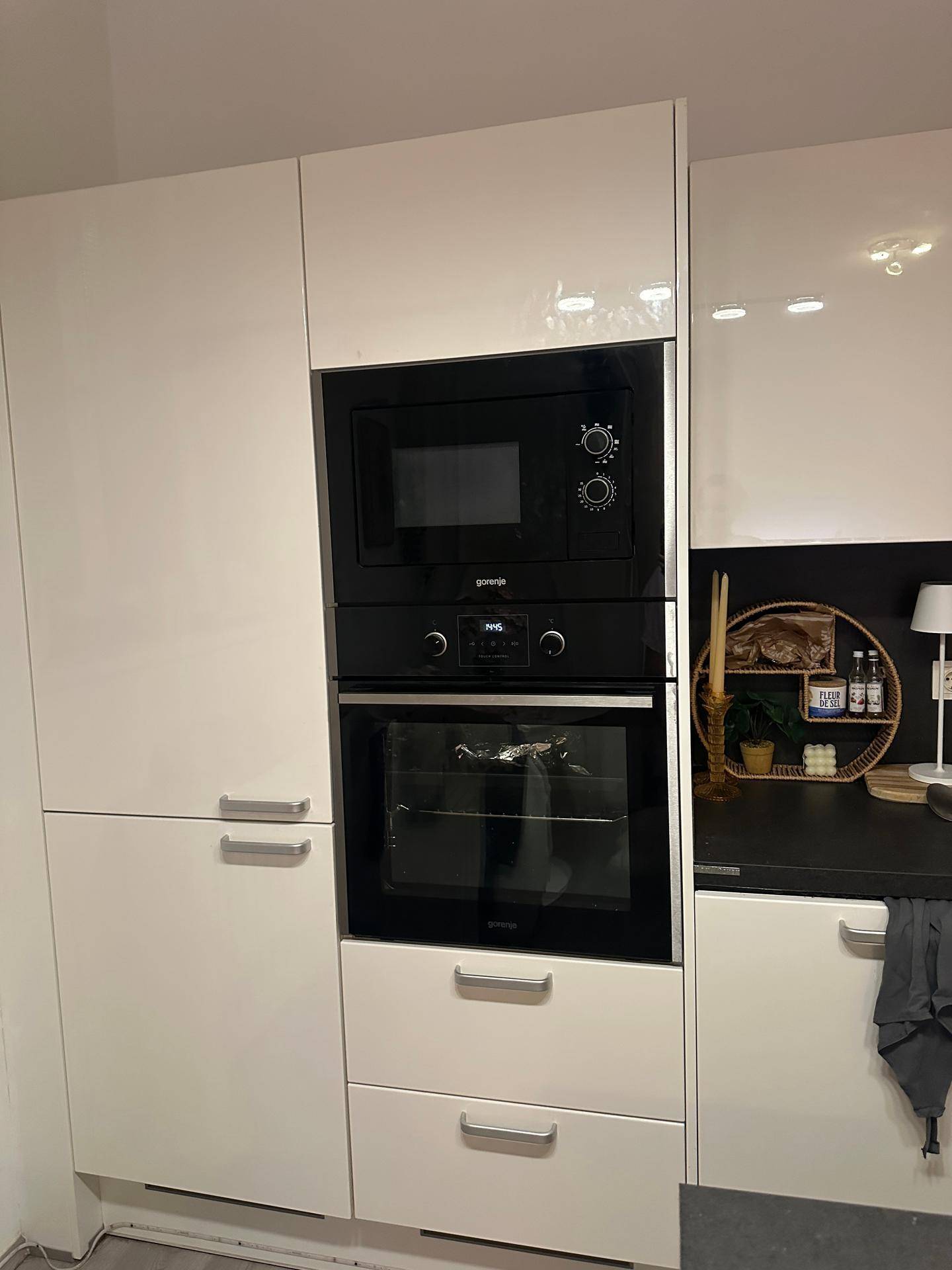 Moderne Einbauküche mit integriertem Backofen und Mikrowelle in Hochglanz-Fronten.