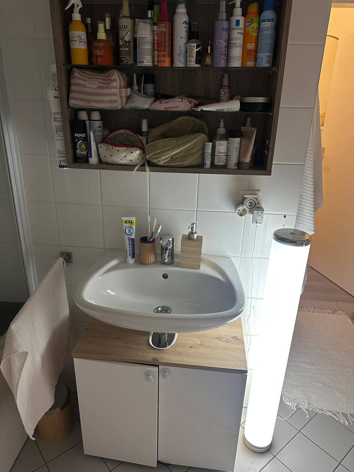 Badezimmer mit modernem Waschbecken, Spiegelschrank und vertikaler Beleuchtung.