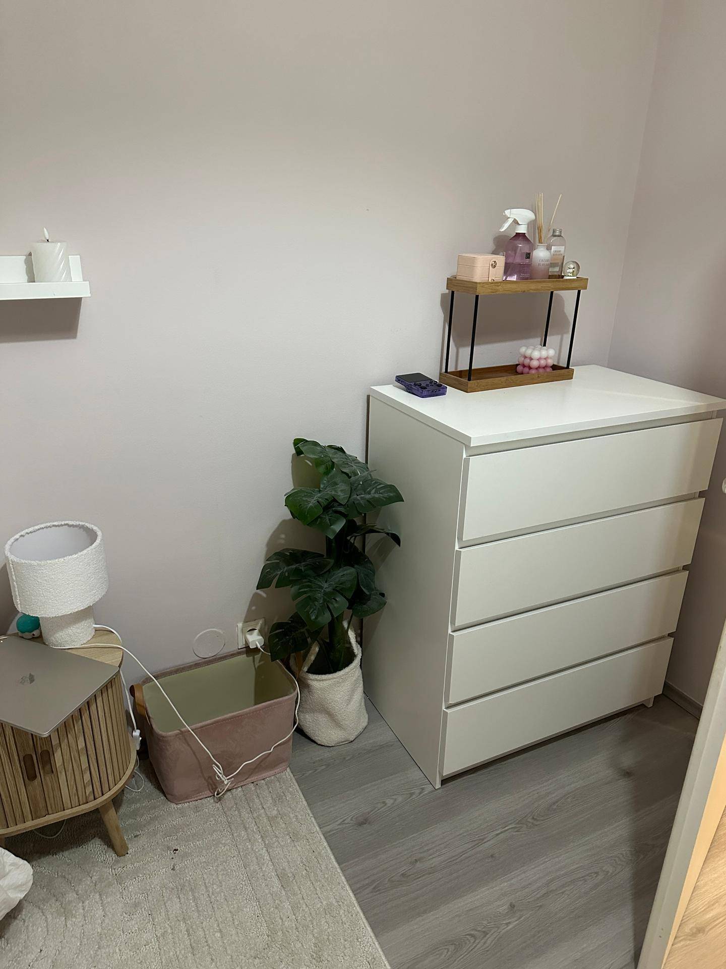 Schlafzimmer mit Kommode, Nachttisch und Pflanzen, die eine gemütliche Atmosphäre schaffen.