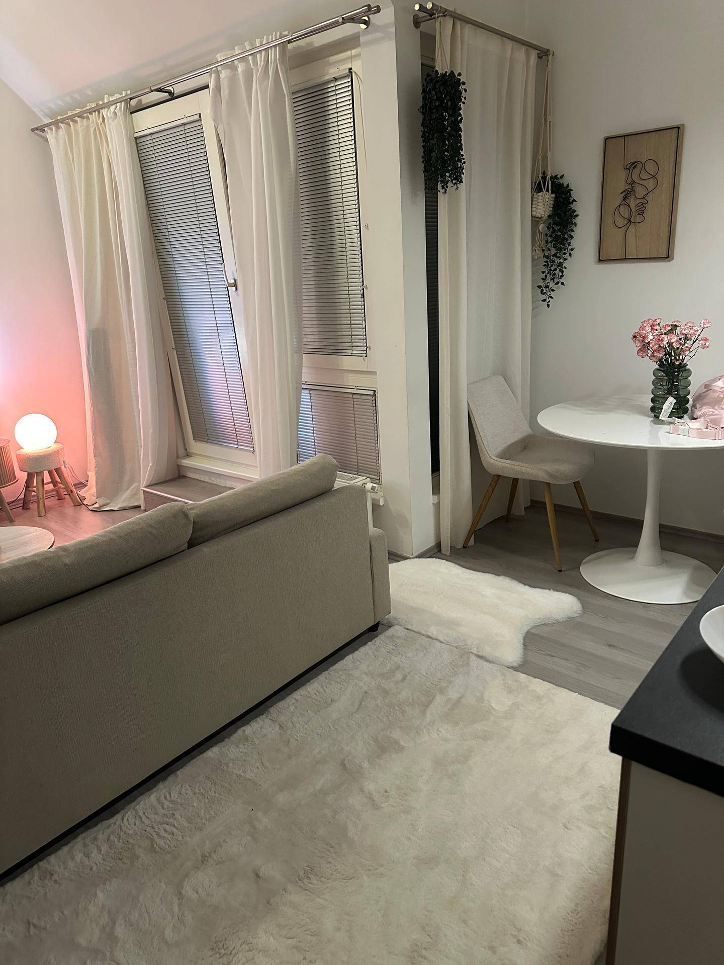 Offener Wohn- und Essbereich mit Sofa, Esstisch und Zugang zu einem französischen Balkon.