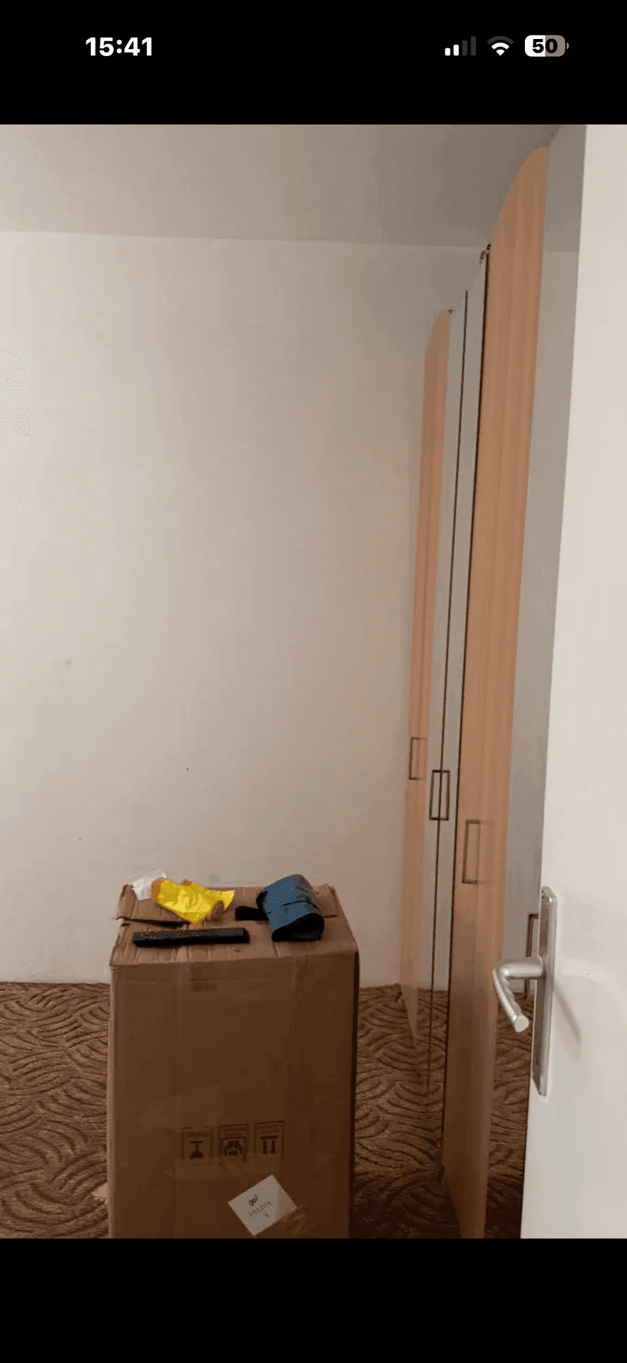 Raum mit gemustertem Teppichboden und Holztüren, die an der Wand lehnen, möglicherweise ein Schlafzimmer.
