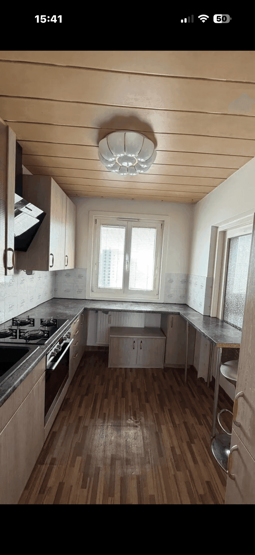 Küche mit Holzdecke, U-förmiger Anordnung, Gasherd, Backofen und Dunstabzugshaube.