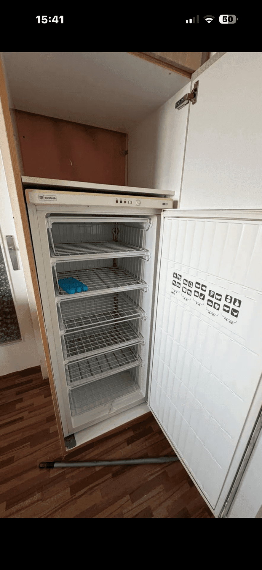 Hoher Gefrierschrank in einer Küche oder einem Hauswirtschaftsraum mit Holzfußboden.
