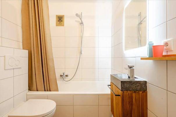 Modernes Badezimmer mit Badewanne, Duschvorhang und einem Waschbecken mit Holzunterschrank.