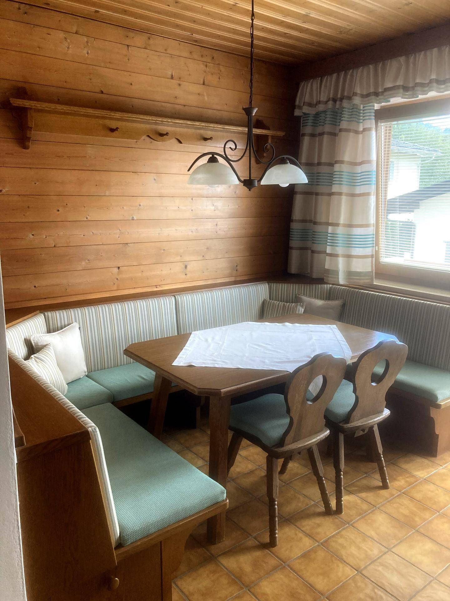 Rustikaler Essbereich mit Holztäfelung, Eckbank und traditionellen Holzmöbeln, ideal für gemütliche Mahlzeiten.
