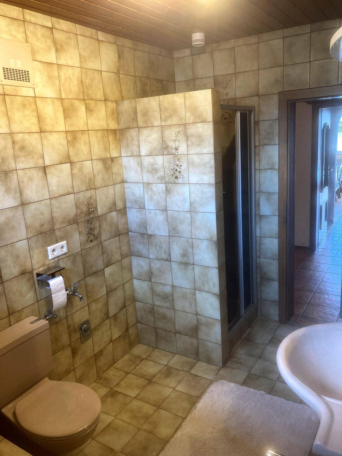 Gefliestes Badezimmer mit Dusche und WC, ausgestattet in einem traditionellen Stil mit Erdtönen.