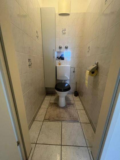 Separates Gäste-WC mit Toilette, Fliesen an Wänden und Boden.