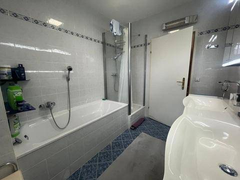 Helles Badezimmer mit Badewanne, Duschkabine und zwei Waschbecken.