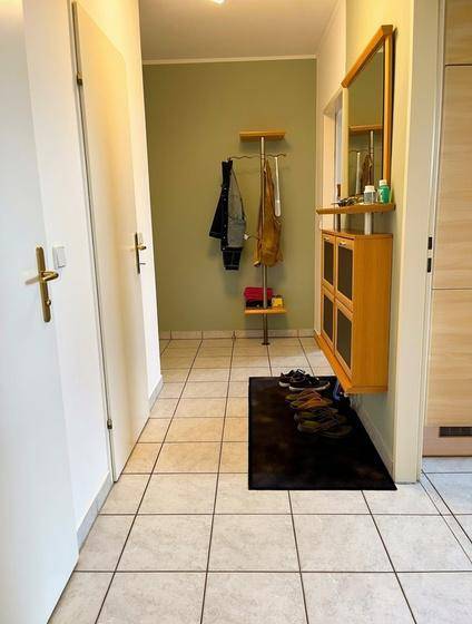 Eingangsbereich mit Fliesenboden, Garderobe und Spiegel, hell und einladend.