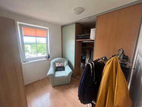 Helles Zimmer mit Fenster, Holzboden und integriertem Schrankbereich.