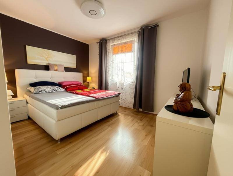 Gemütliches Schlafzimmer mit Doppelbett, Holzboden und Fenster mit Vorhängen.