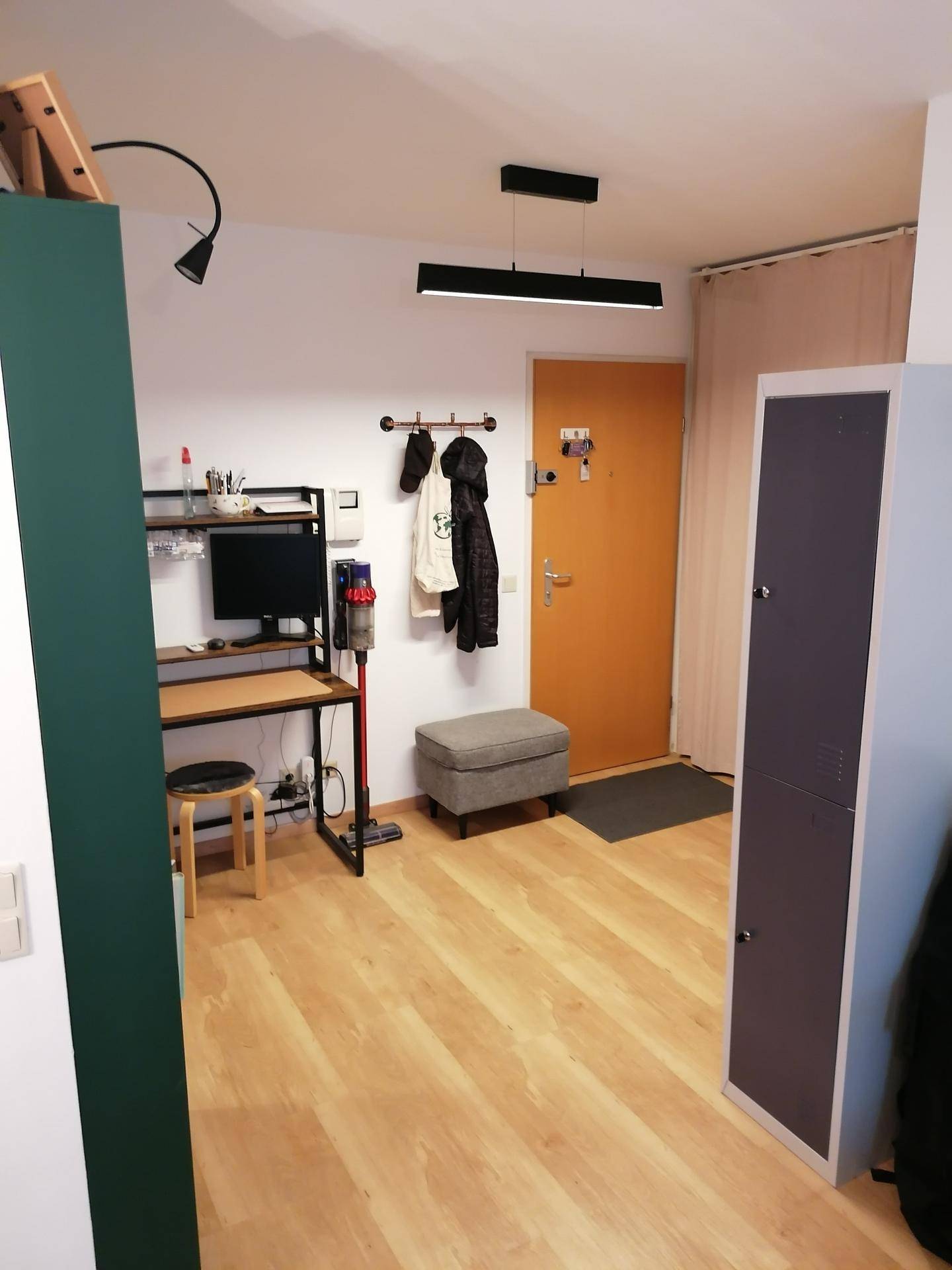 Eingangsbereich mit Garderobe, kleinem Arbeitsplatz und hellem Laminatboden.