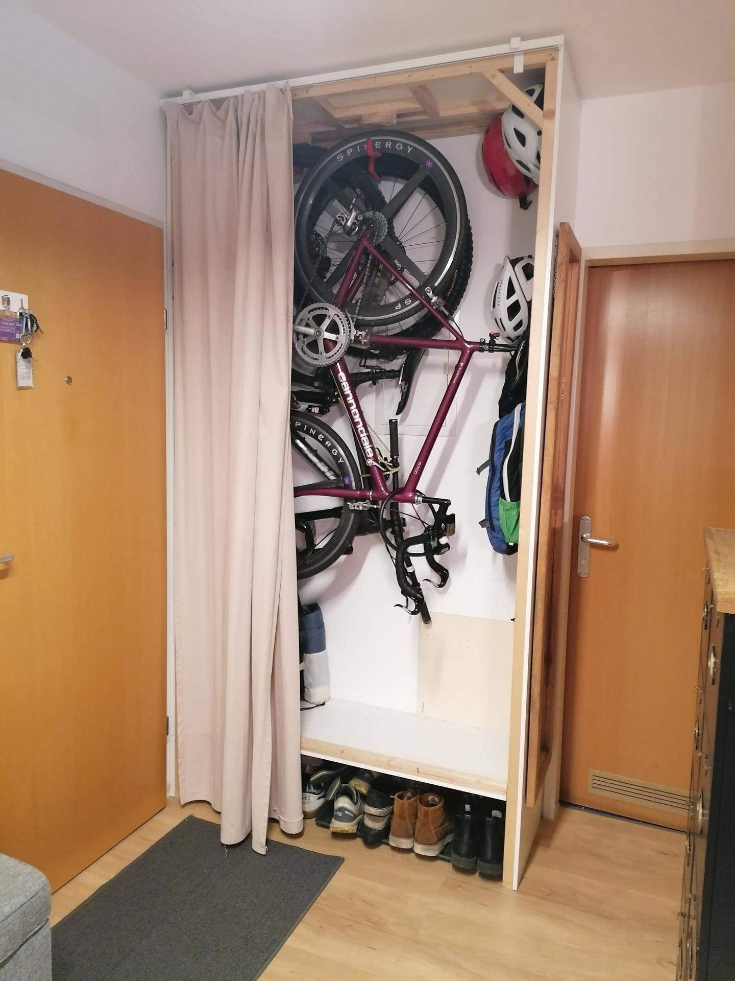 Praktischer Stauraum im Flur mit Fahrradhalterung und Schuhablage hinter einem Vorhang.