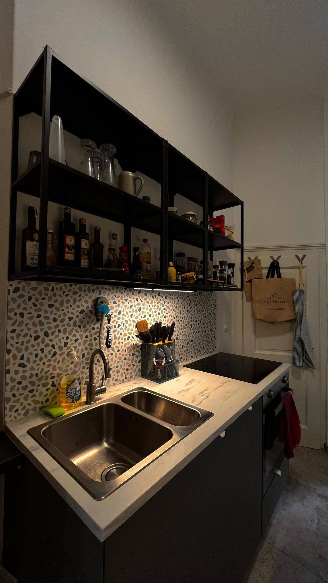 Moderne Küche mit Doppelspüle, Induktionskochfeld und offenen schwarzen Regalen.