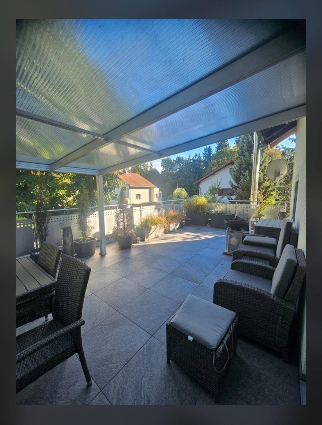 Überdachte Terrasse mit modernen Outdoor-Möbeln und Blick auf die umliegende Natur.