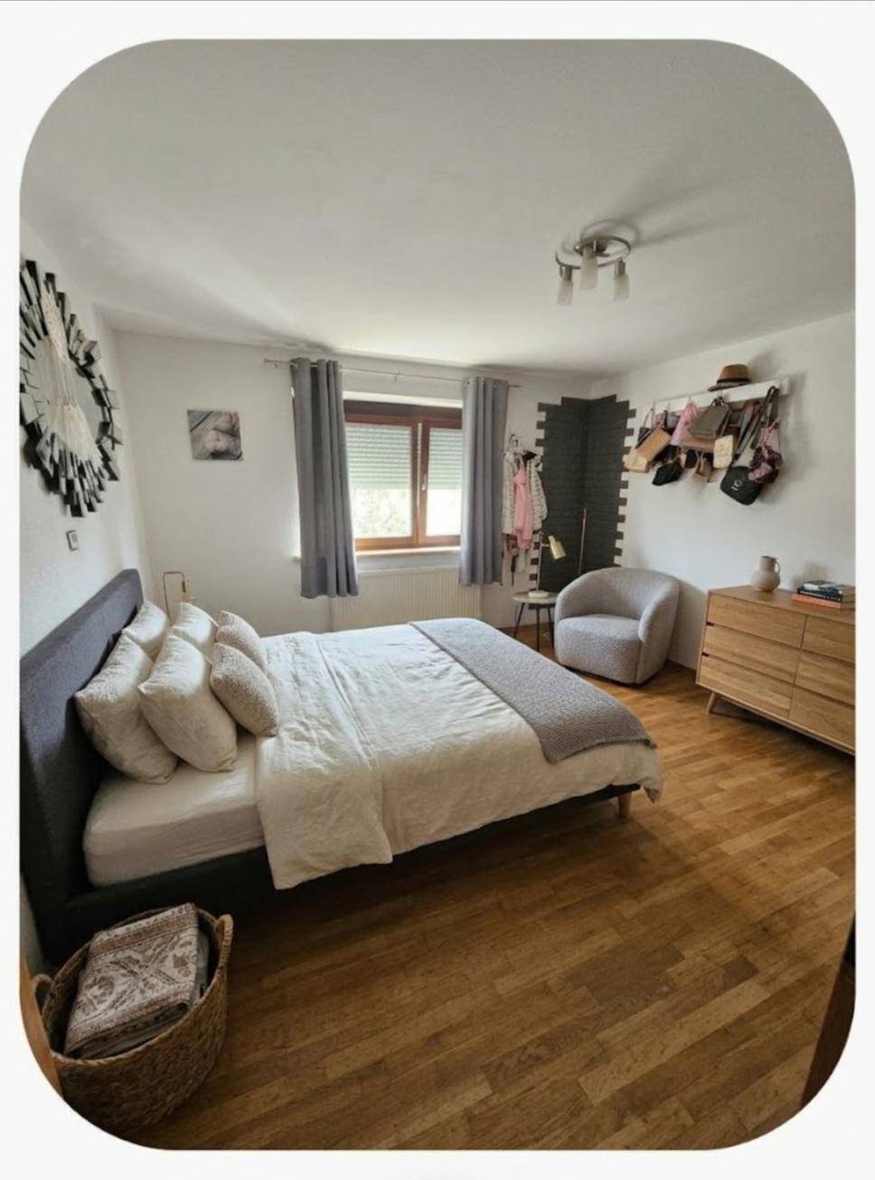 Schlafzimmer mit Doppelbett, Holzboden und einem Fenster, das für natürliches Licht sorgt.