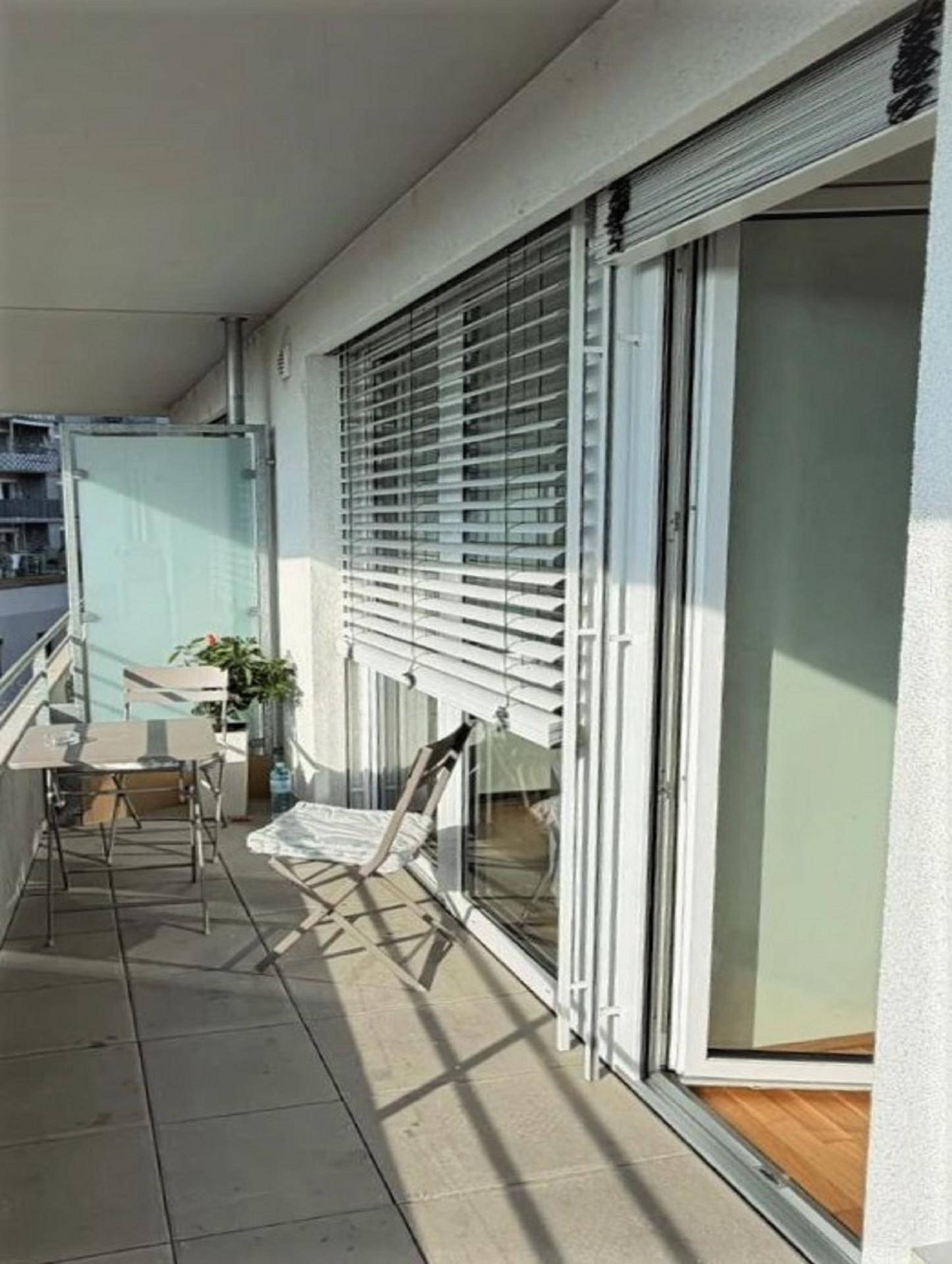 Sonniger Balkon mit Fliesenboden, bequemen Sitzgelegenheiten und Blick auf die Umgebung.