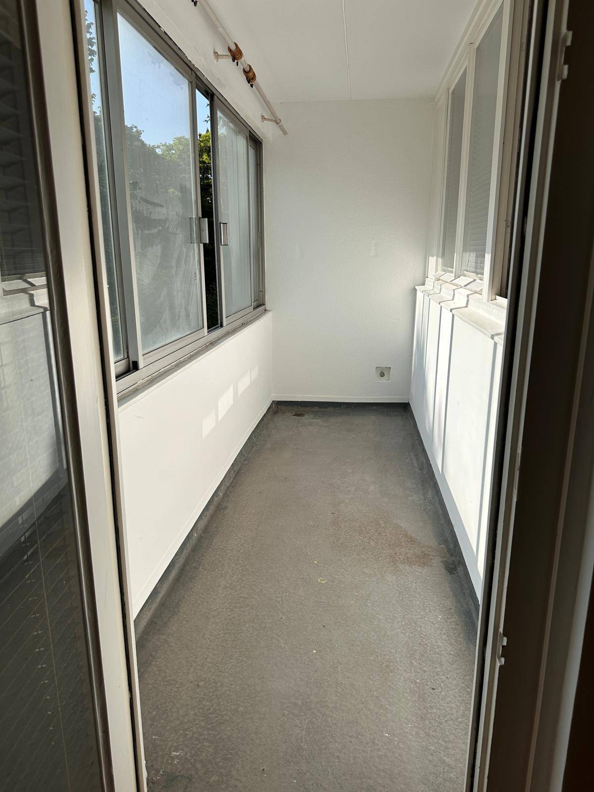 Helle Loggia mit weißen Wänden und Blick ins Grüne, ideal zum Entspannen.