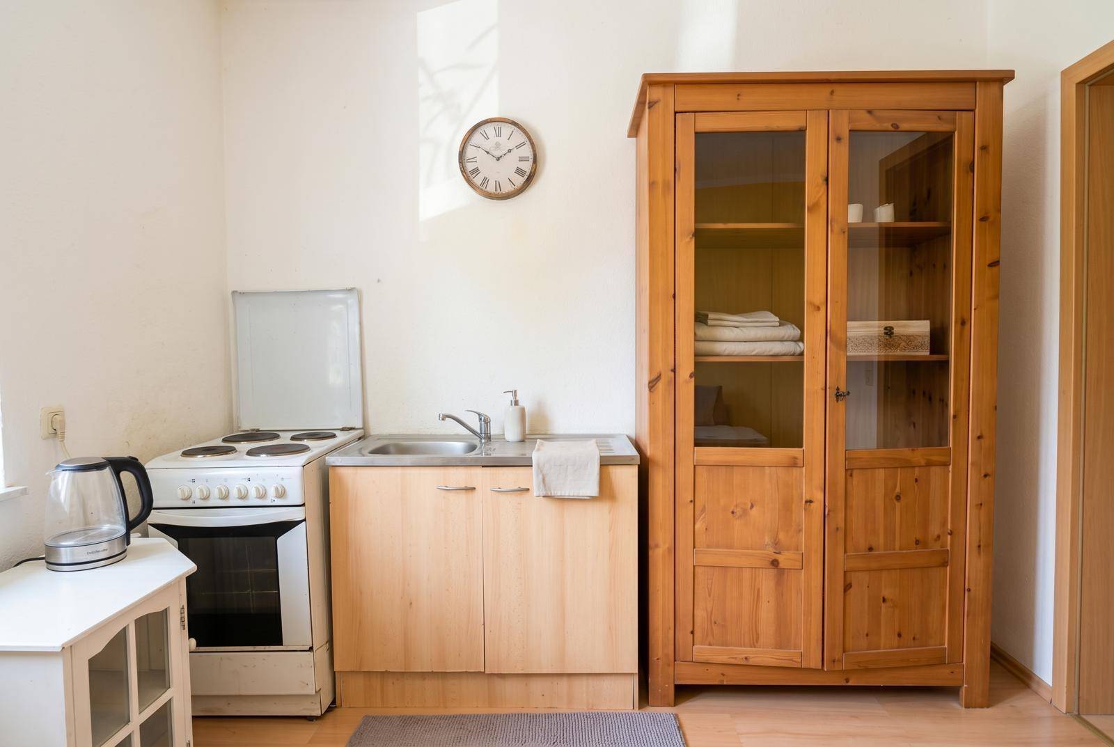 Funktionale Küchenzeile mit Spüle, Herd und Holzschrank in einem hellen Raum.