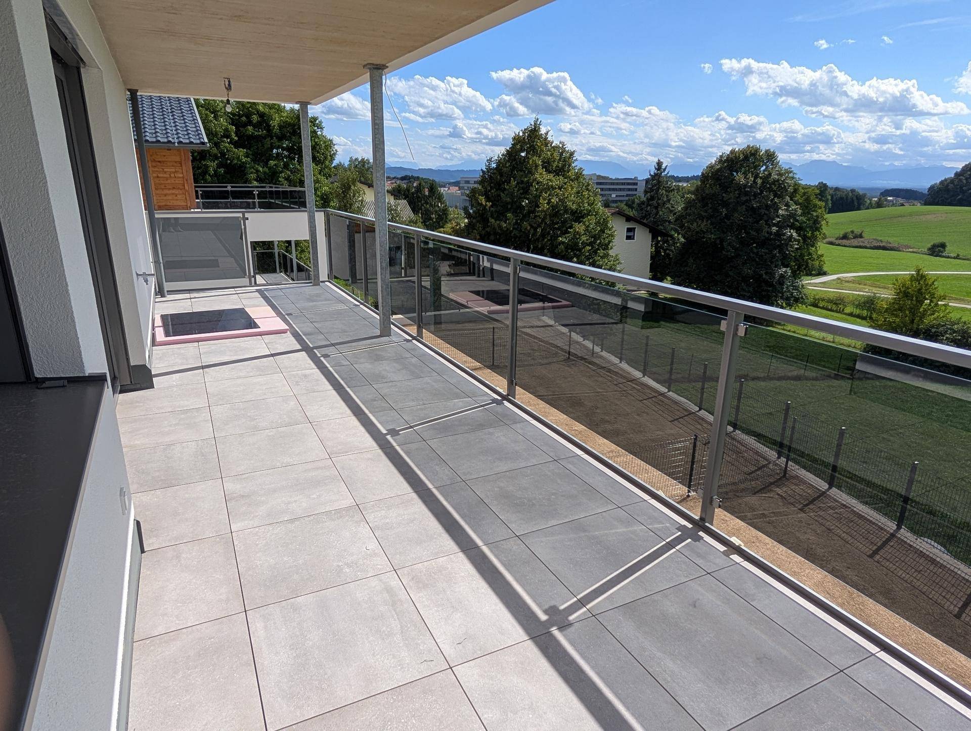 Geräumiger Balkon mit Fliesenboden und Glasgeländer bietet weite Aussicht.