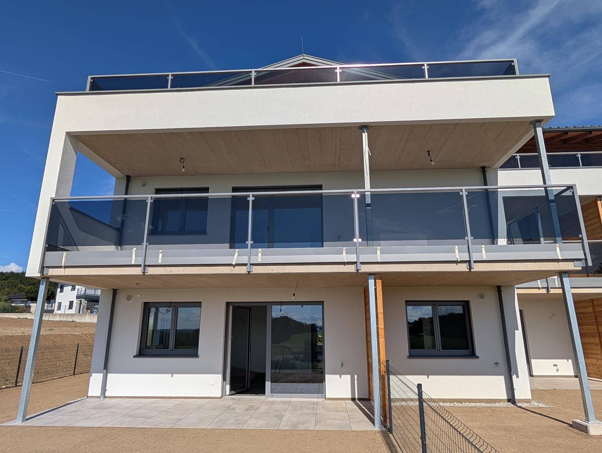 Nahaufnahme der modernen Fassade mit großen Balkonen und Terrassen im Erdgeschoss.