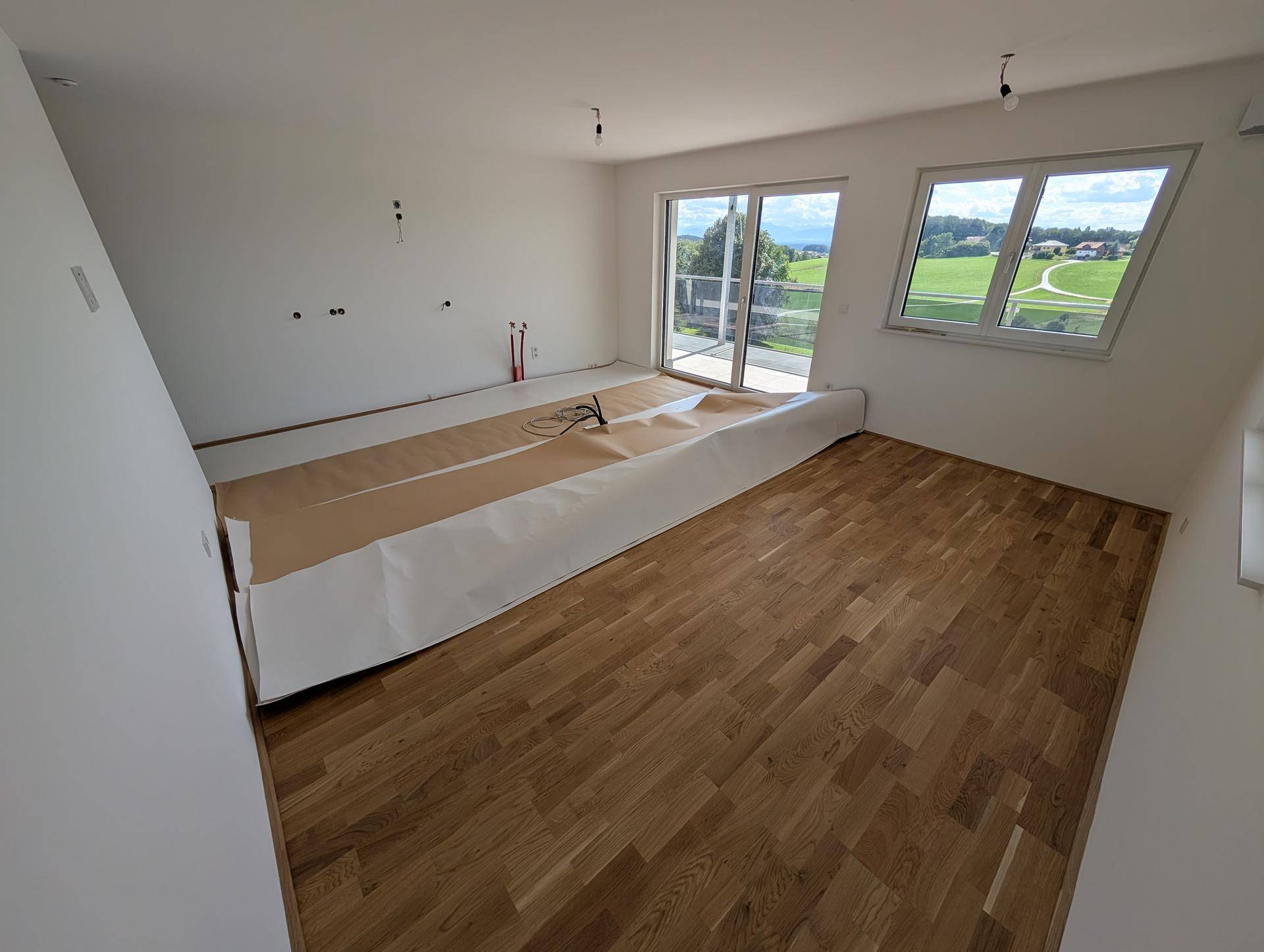 Lichtdurchfluteter Wohnbereich mit großen Fenstern und Zugang zu einem Außenbereich.
