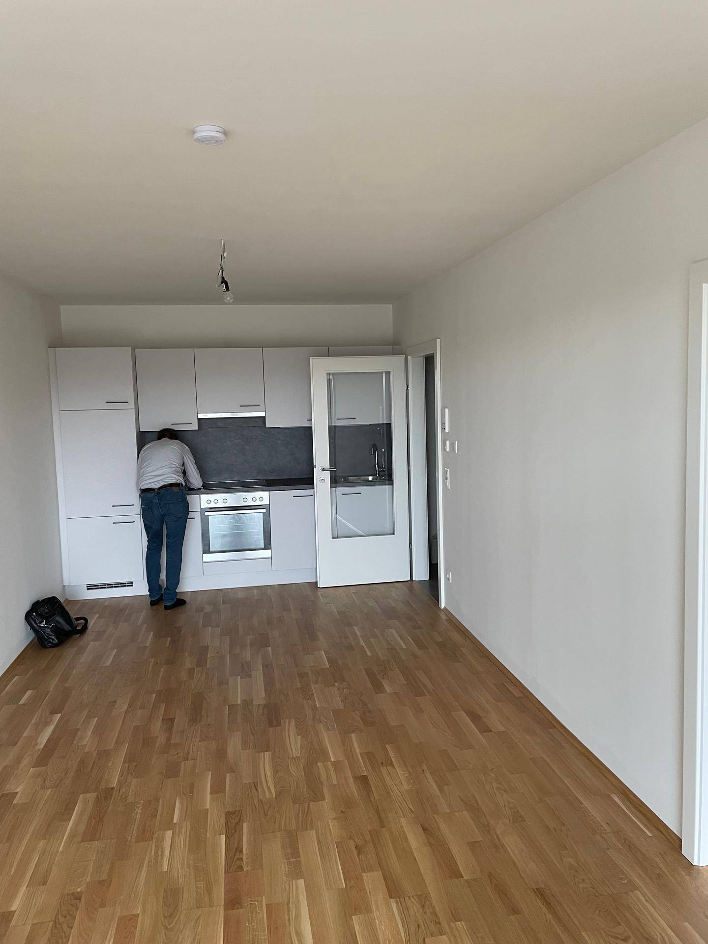 Offene Küche mit weißen Schränken, integrierten Geräten und Parkettboden in einem modernen Wohnbereich.