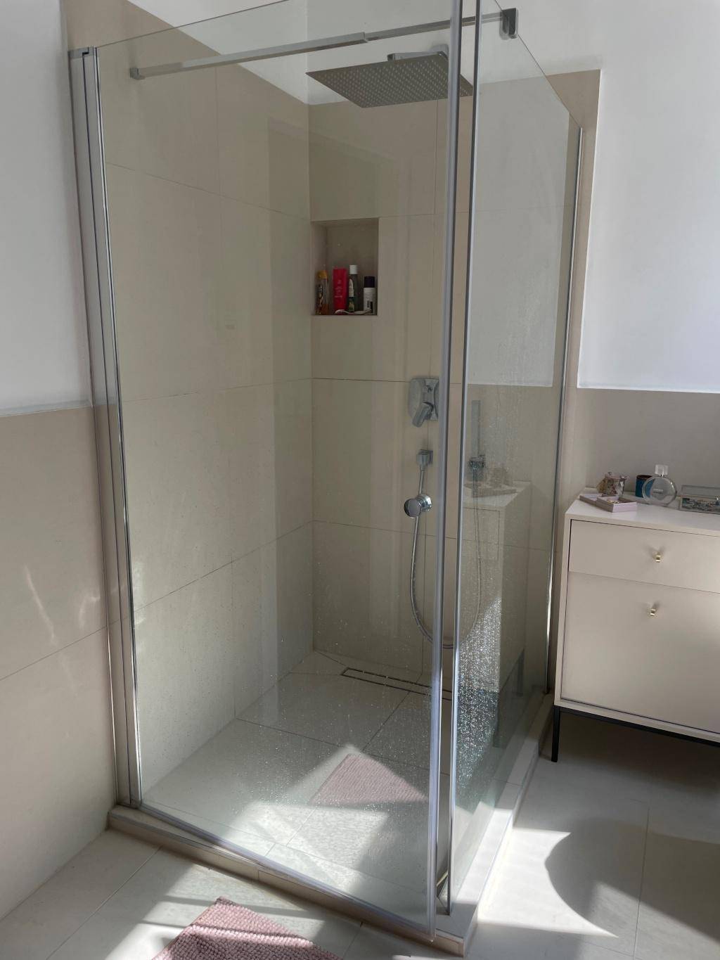 Modernes Badezimmer mit großer begehbarer Dusche und hellen Fliesen.