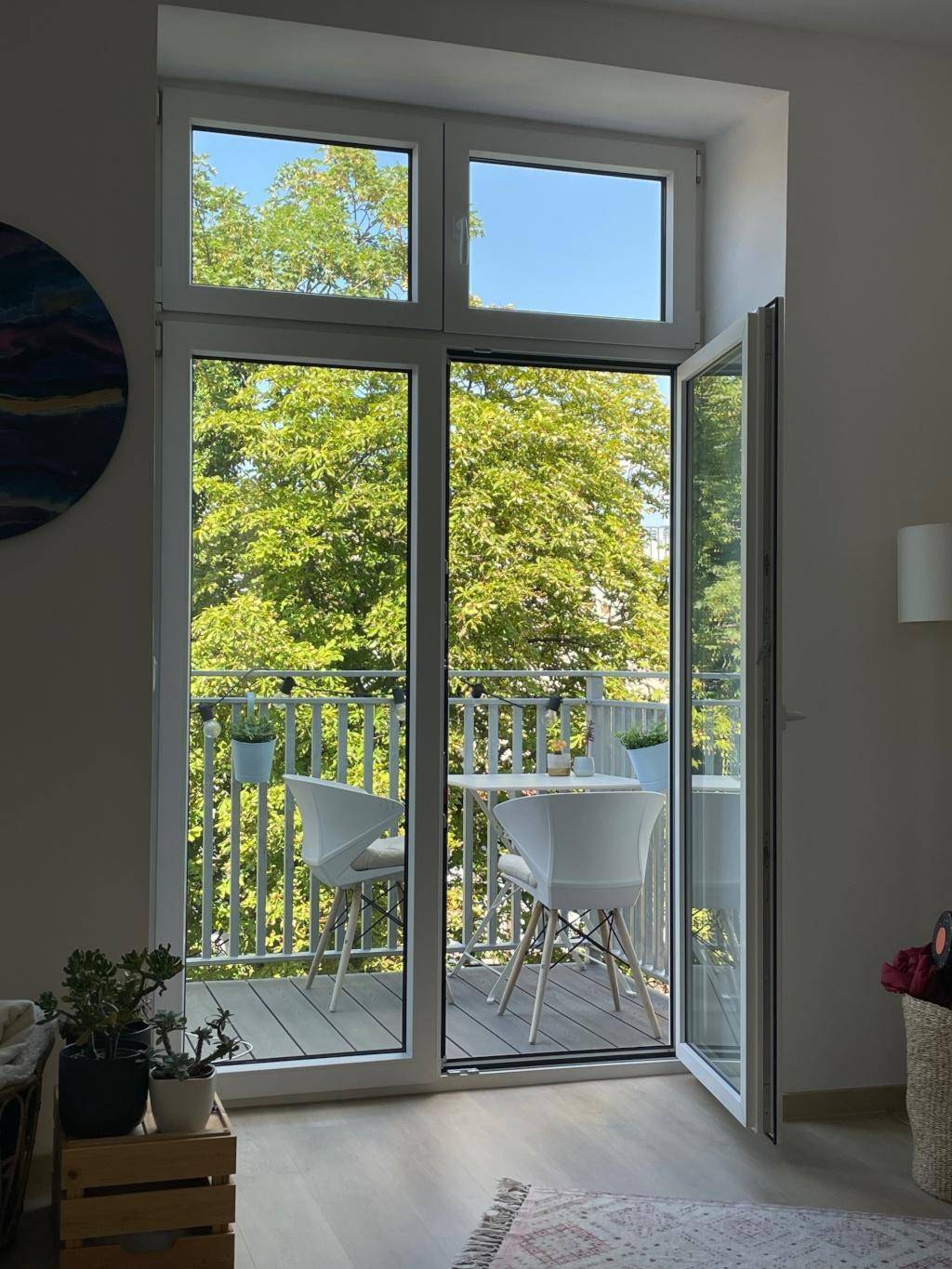 Lichtdurchflutetes Wohnzimmer mit Balkonzugang, Blick ins Grüne und modernen Fenstern.