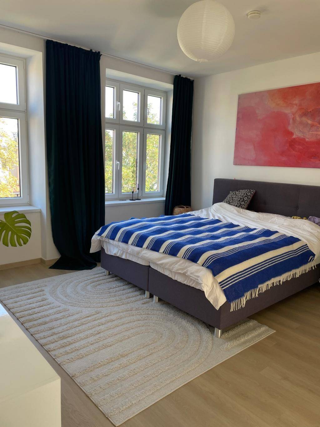 Geräumiges Schlafzimmer mit Doppelbett, dunklen Vorhängen und hellem Holzboden.