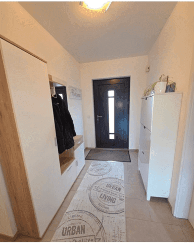 Heller Eingangsbereich mit Garderobe, Schuhschrank und heller Fliesenboden.