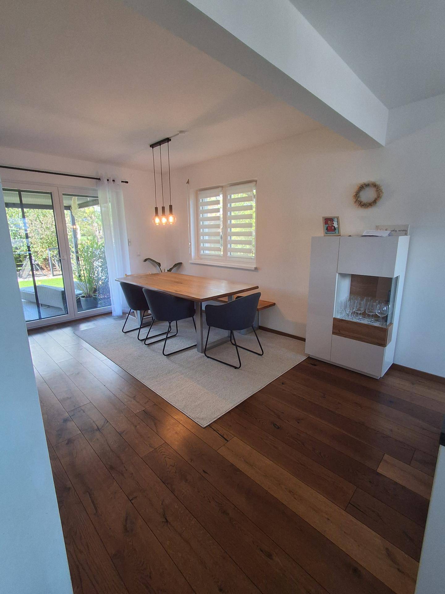 Heller Essbereich mit Holzboden, großem Esstisch und Zugang zur Terrasse.