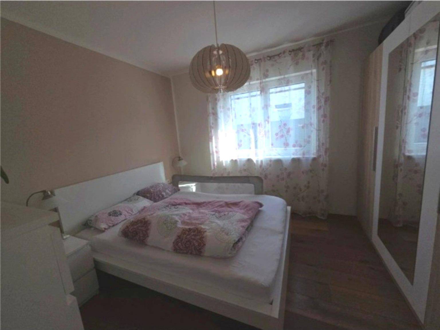 Schlafzimmer mit Doppelbett, Spiegelschrank und Holzboden.