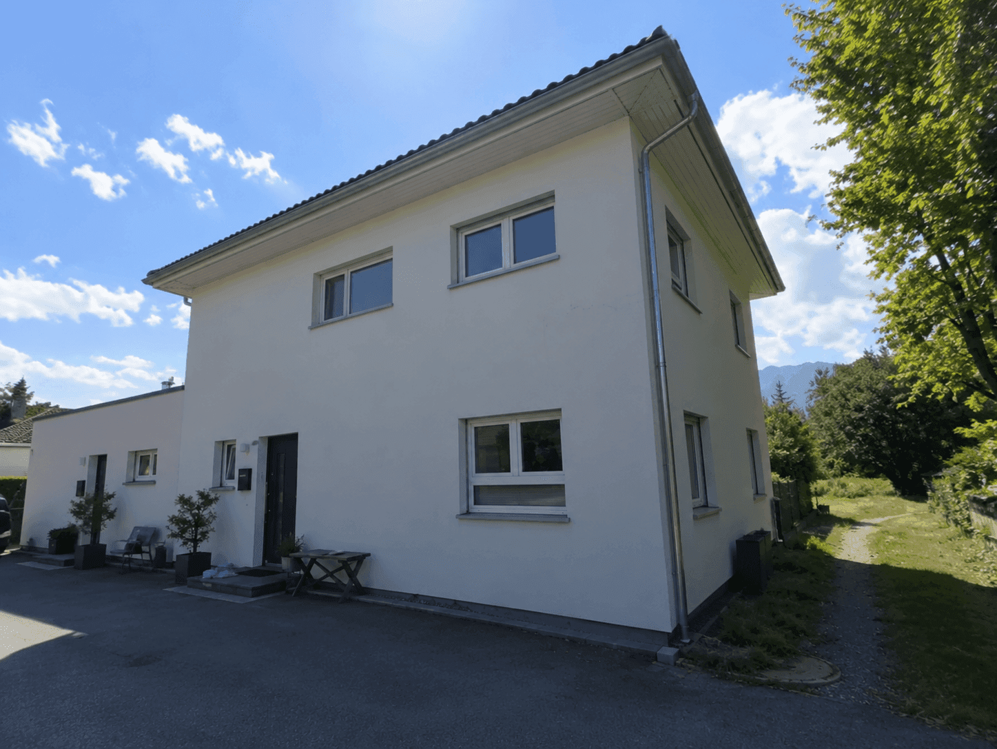 Seitenansicht des modernen Einfamilienhauses mit weißer Fassade und Satteldach.