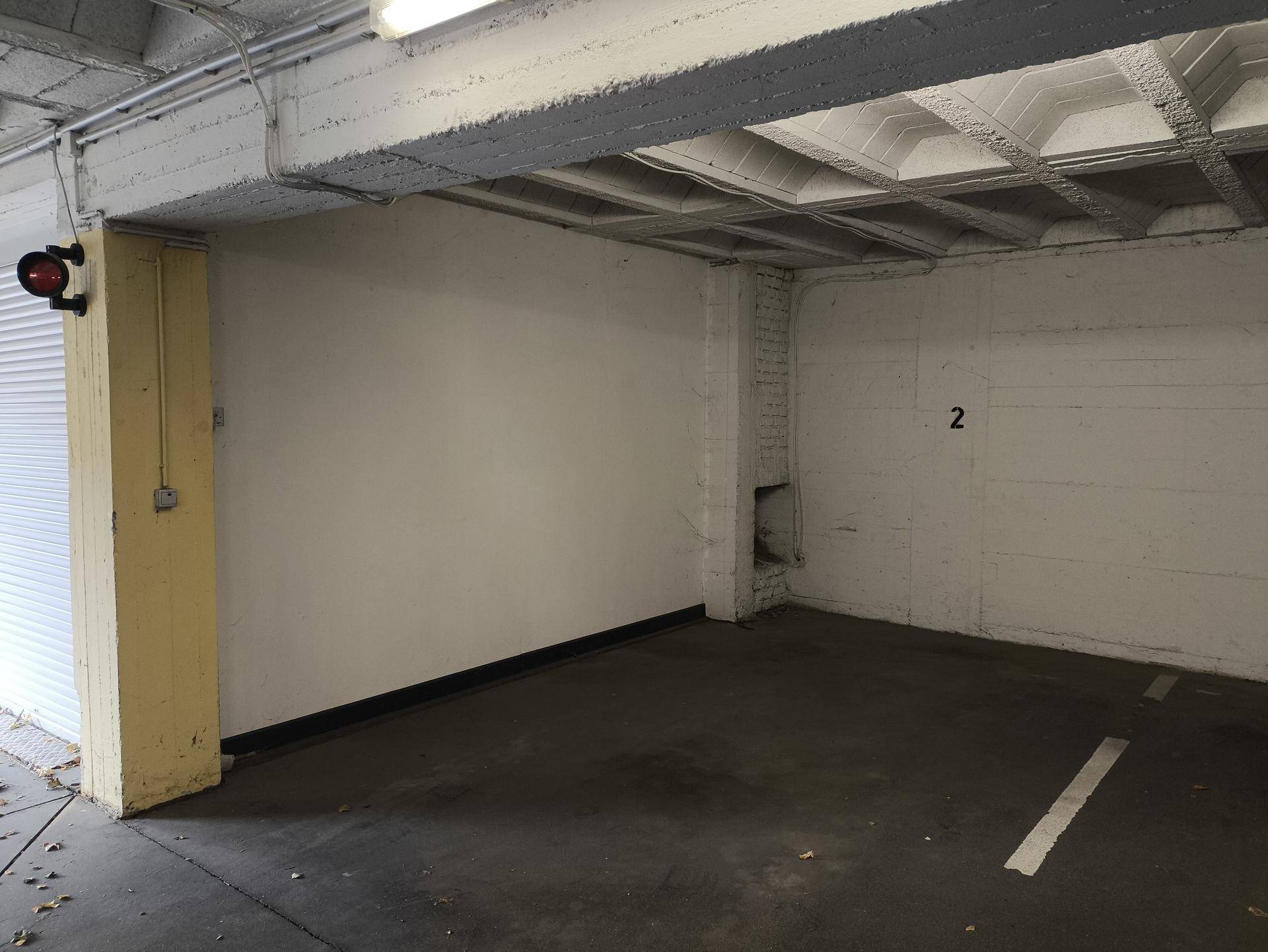 Tiefgaragenstellplatz mit weiß gestrichenen Wänden und sichtbarer Betonstruktur an der Decke.