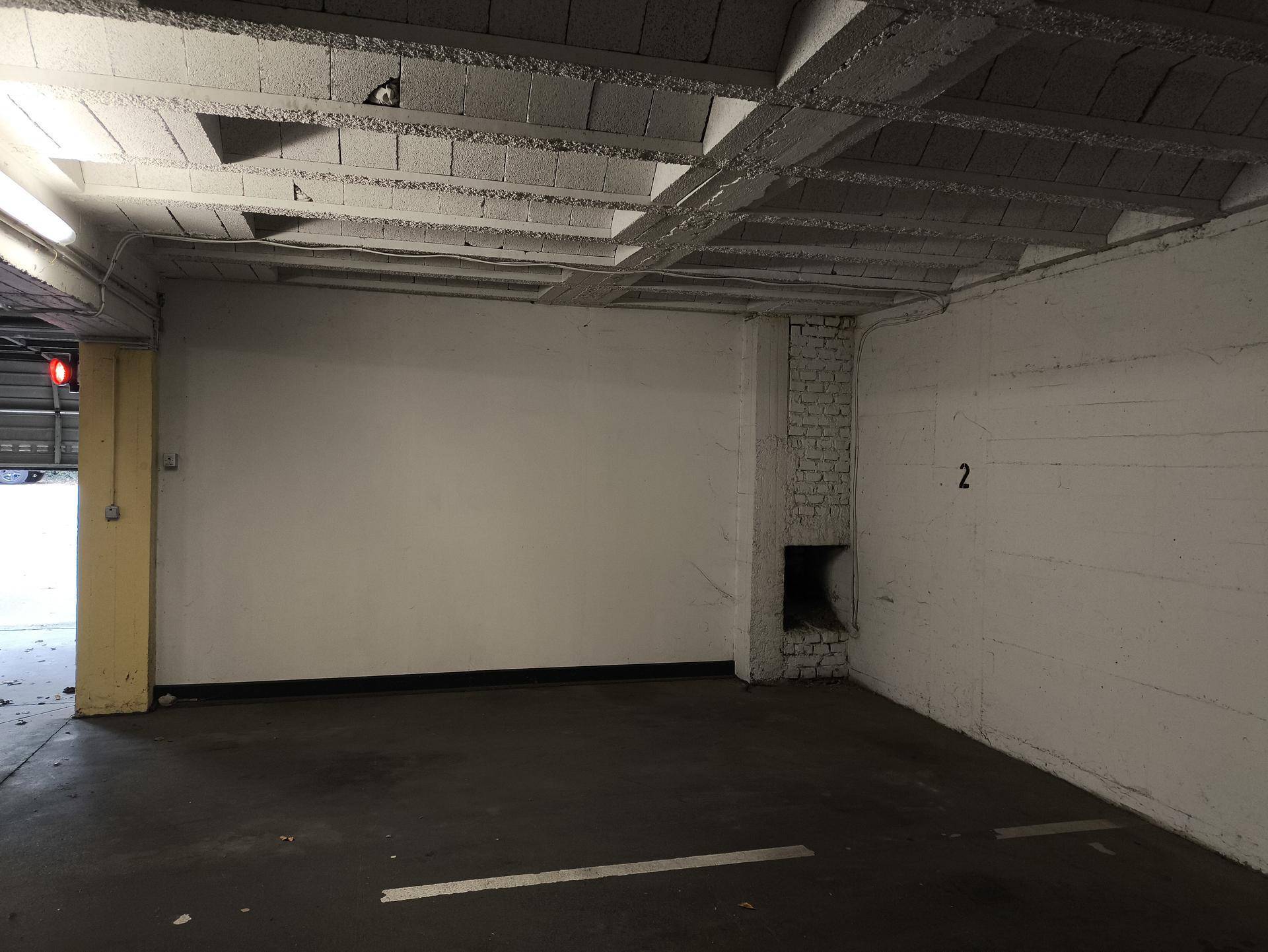 Blick auf einen Tiefgaragenstellplatz mit robusten Betonstrukturen und einfacher Beleuchtung.