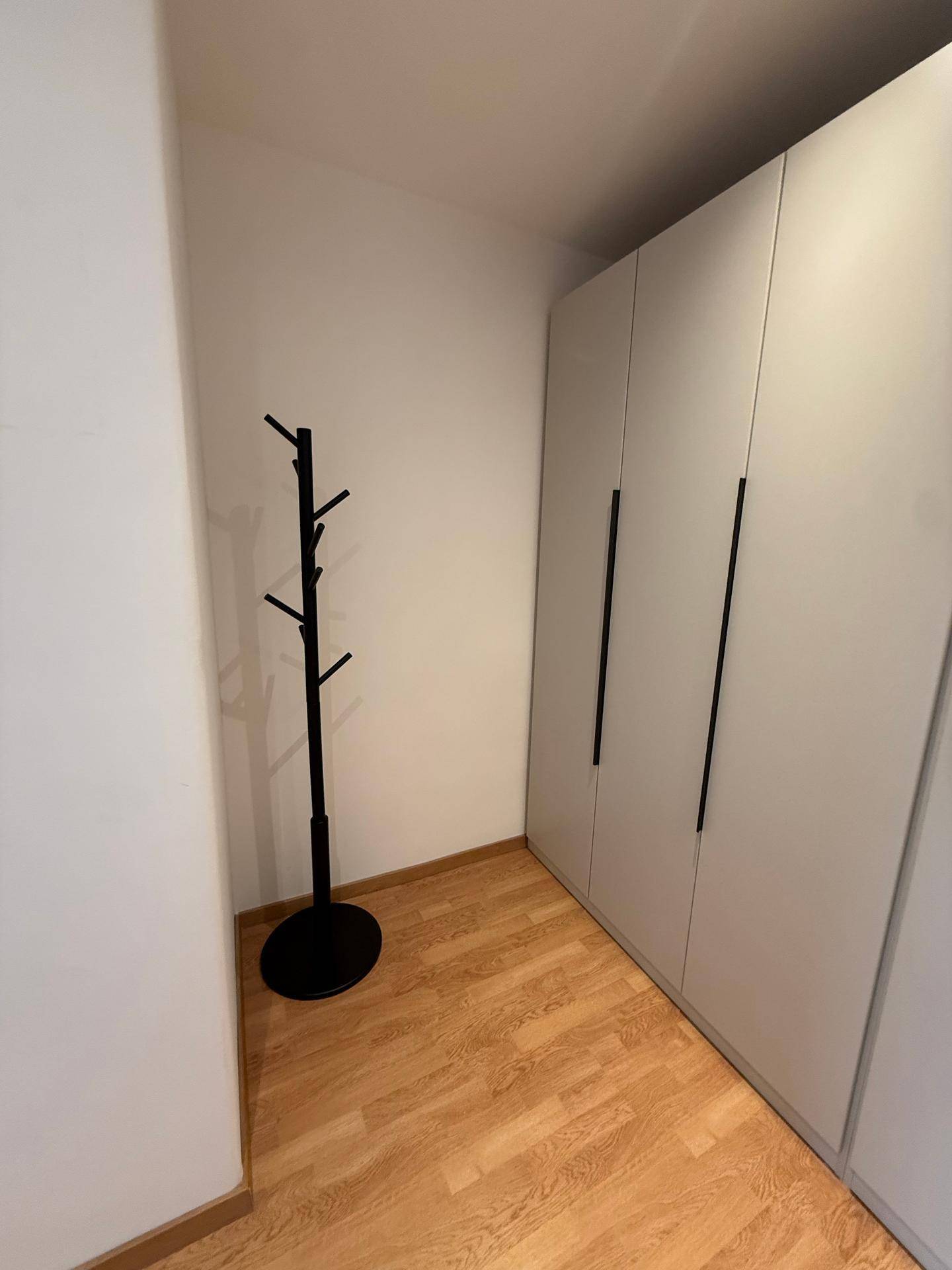 Ecke im Flur mit einem schwarzen Garderobenständer und integrierten Schränken.
