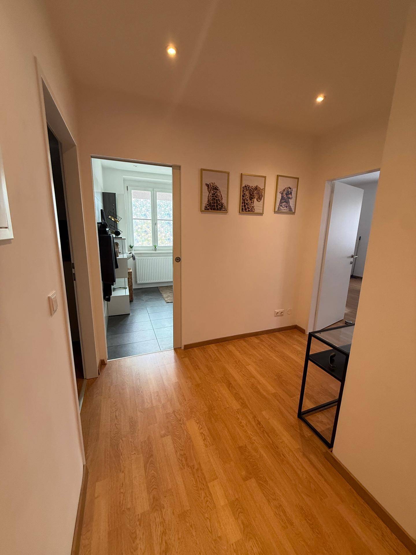 Heller Flur mit Holzfußboden, der den Blick in angrenzende Räume freigibt.