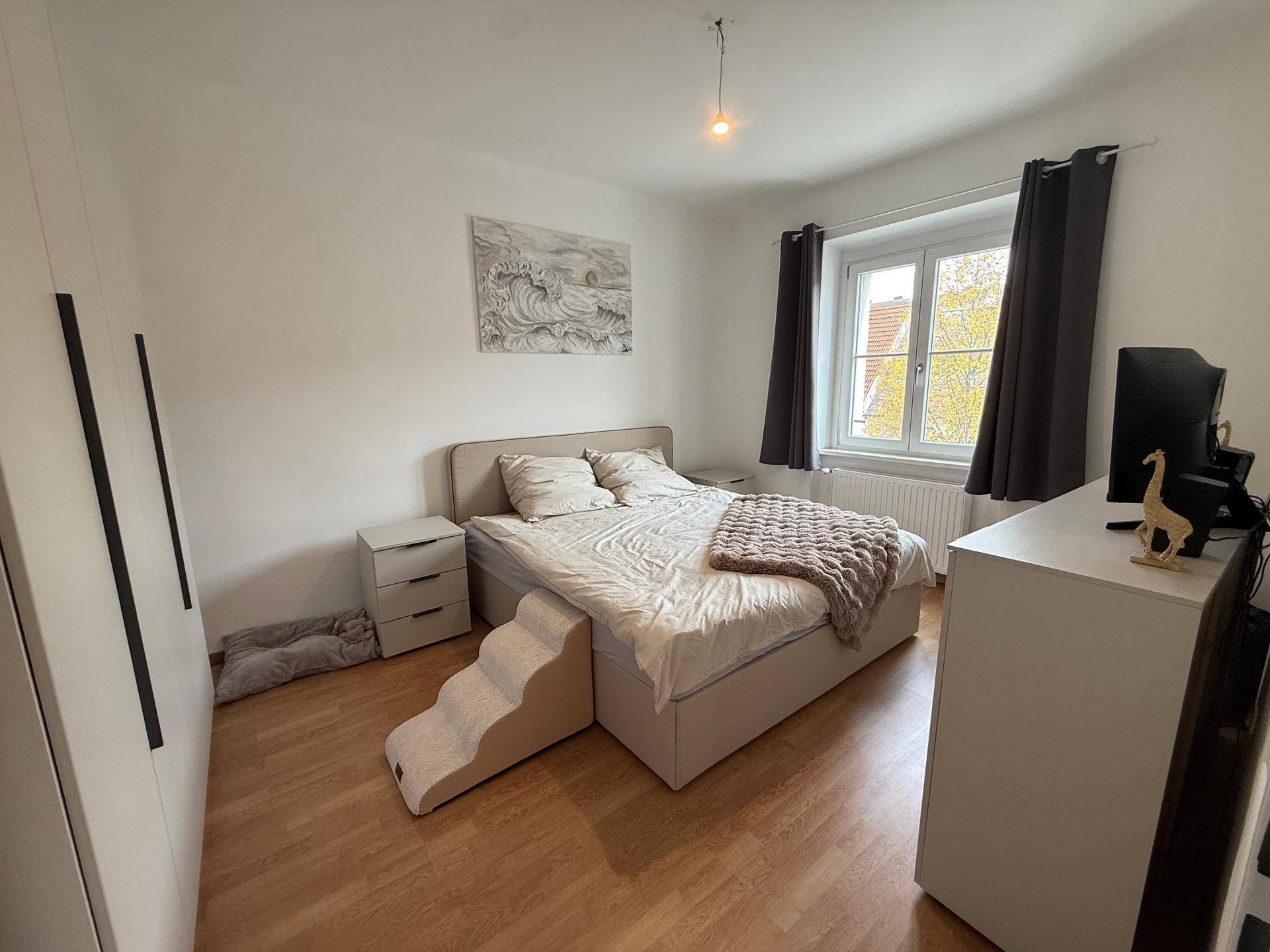Gemütliches Schlafzimmer mit Doppelbett, Nachttischen und Fenster mit Blick nach draußen.