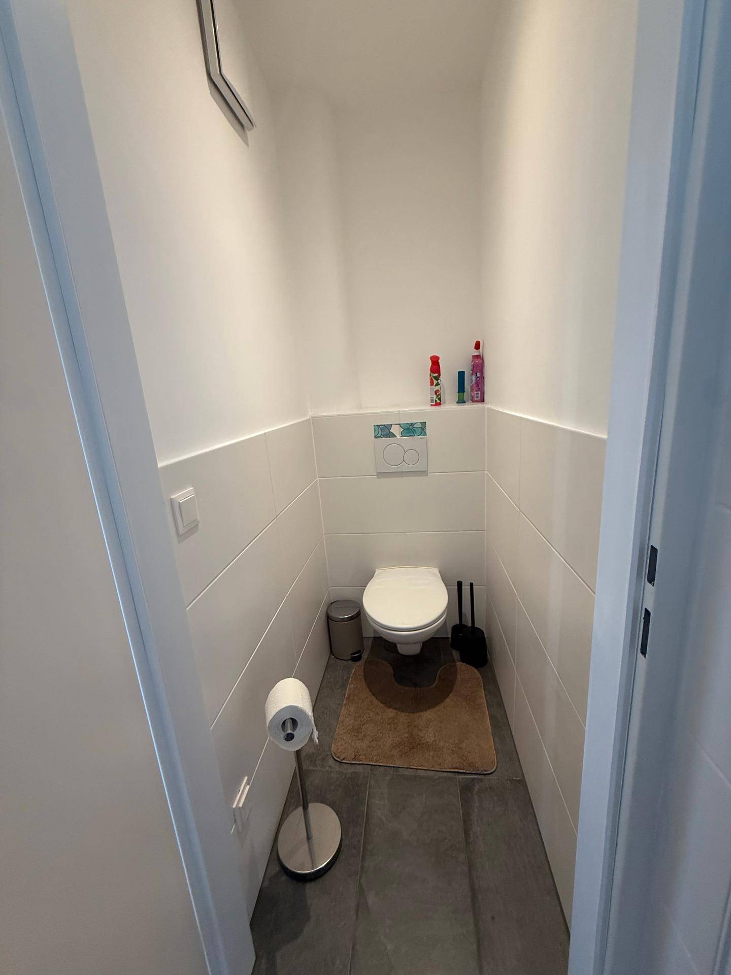 Kleines Gäste-WC mit Wand-WC und dunklen Bodenfliesen.