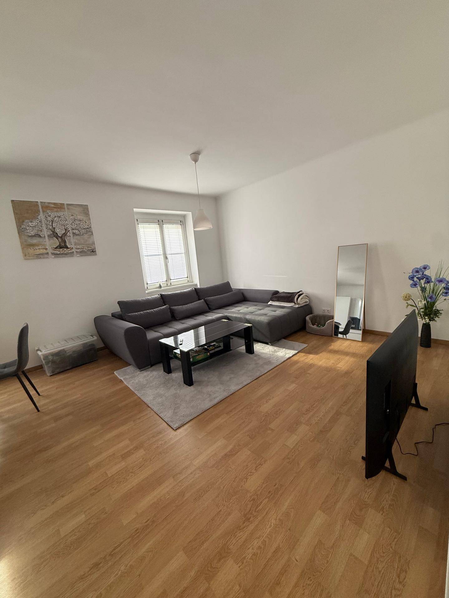 Geräumiges Wohnzimmer mit großem Ecksofa, Couchtisch und Fernseher.