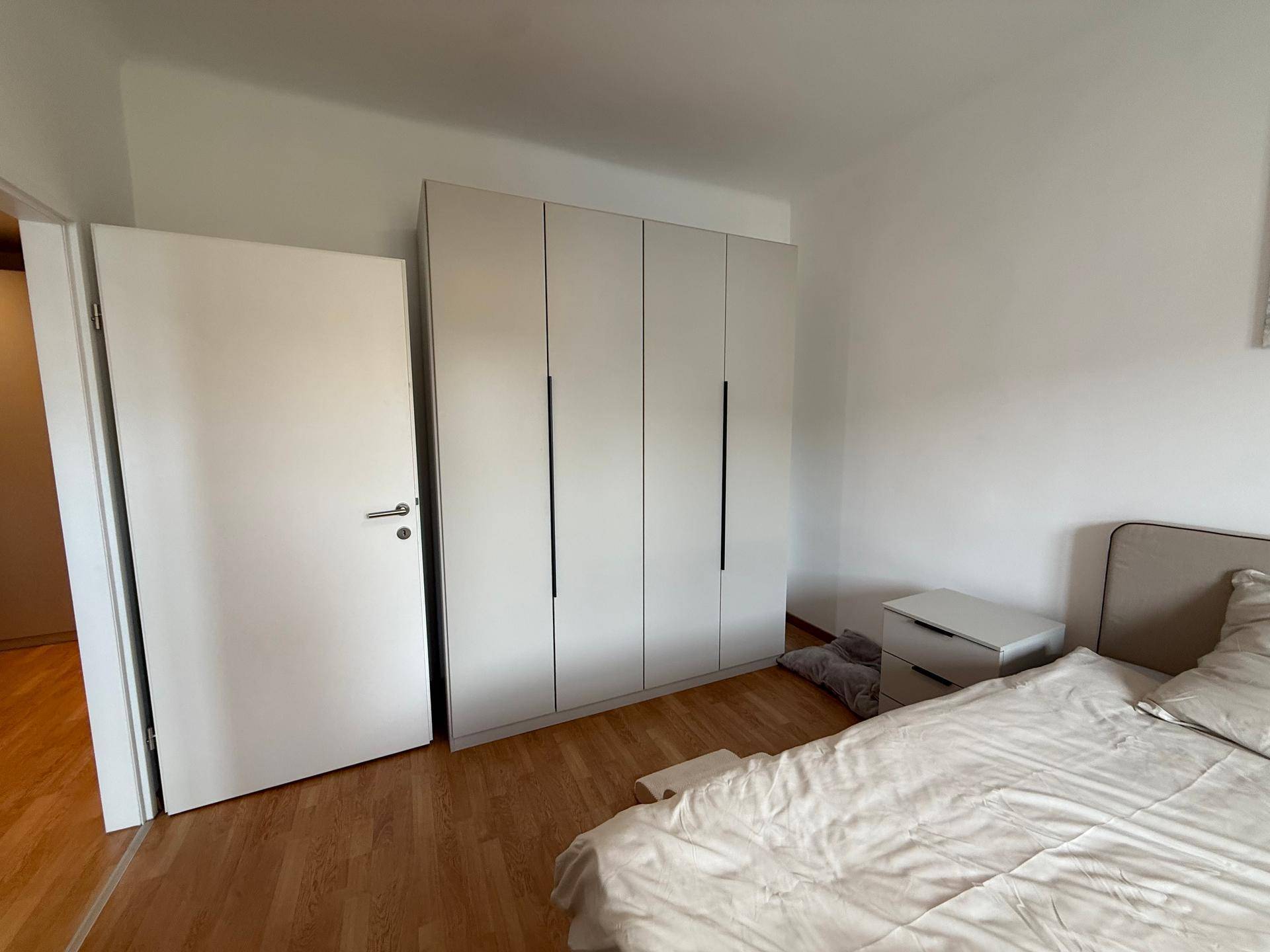Schlafzimmer mit großem Kleiderschrank und hellem Holzfußboden.
