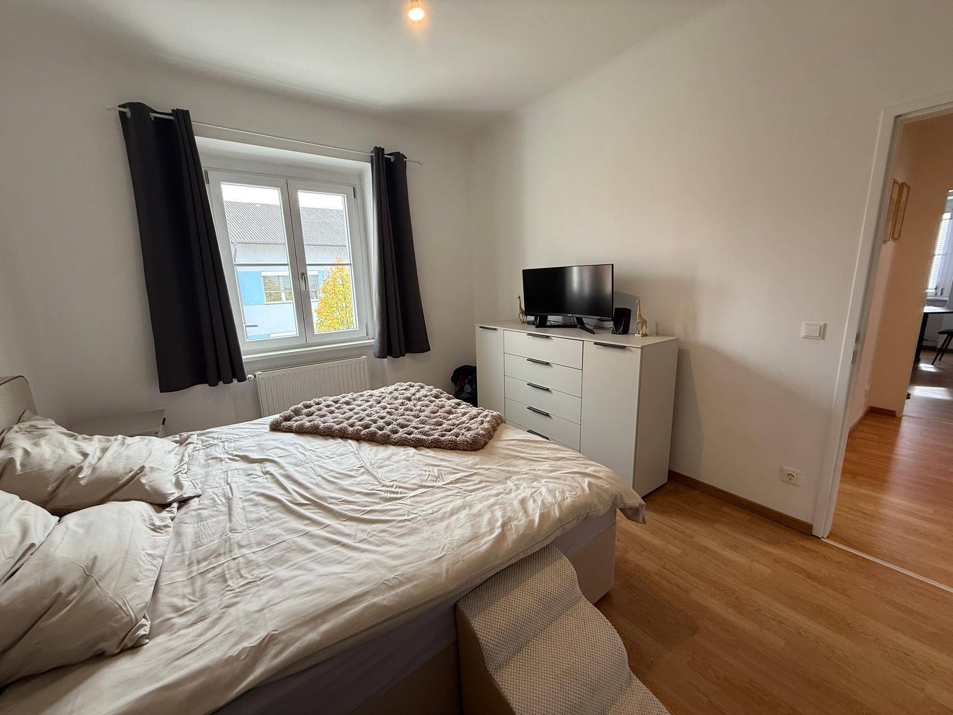 Schlafzimmer mit Bett, Kommode und Fernseher, bietet einen Blick aus dem Fenster.