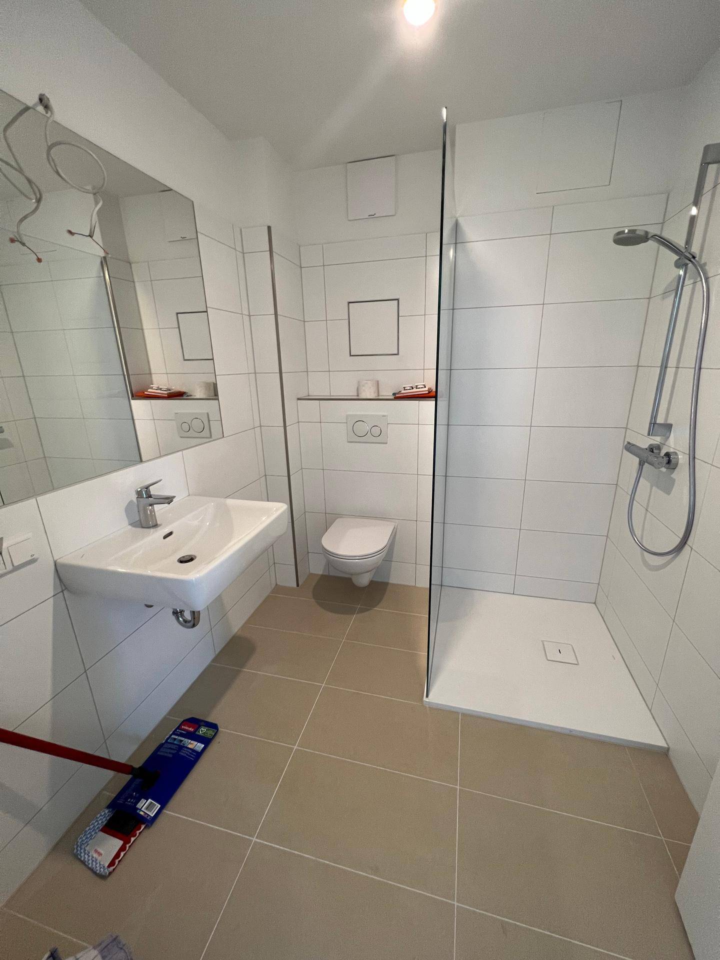 Modernes Badezimmer mit begehbarer Dusche, wandhängendem WC und hellem Fliesenboden.