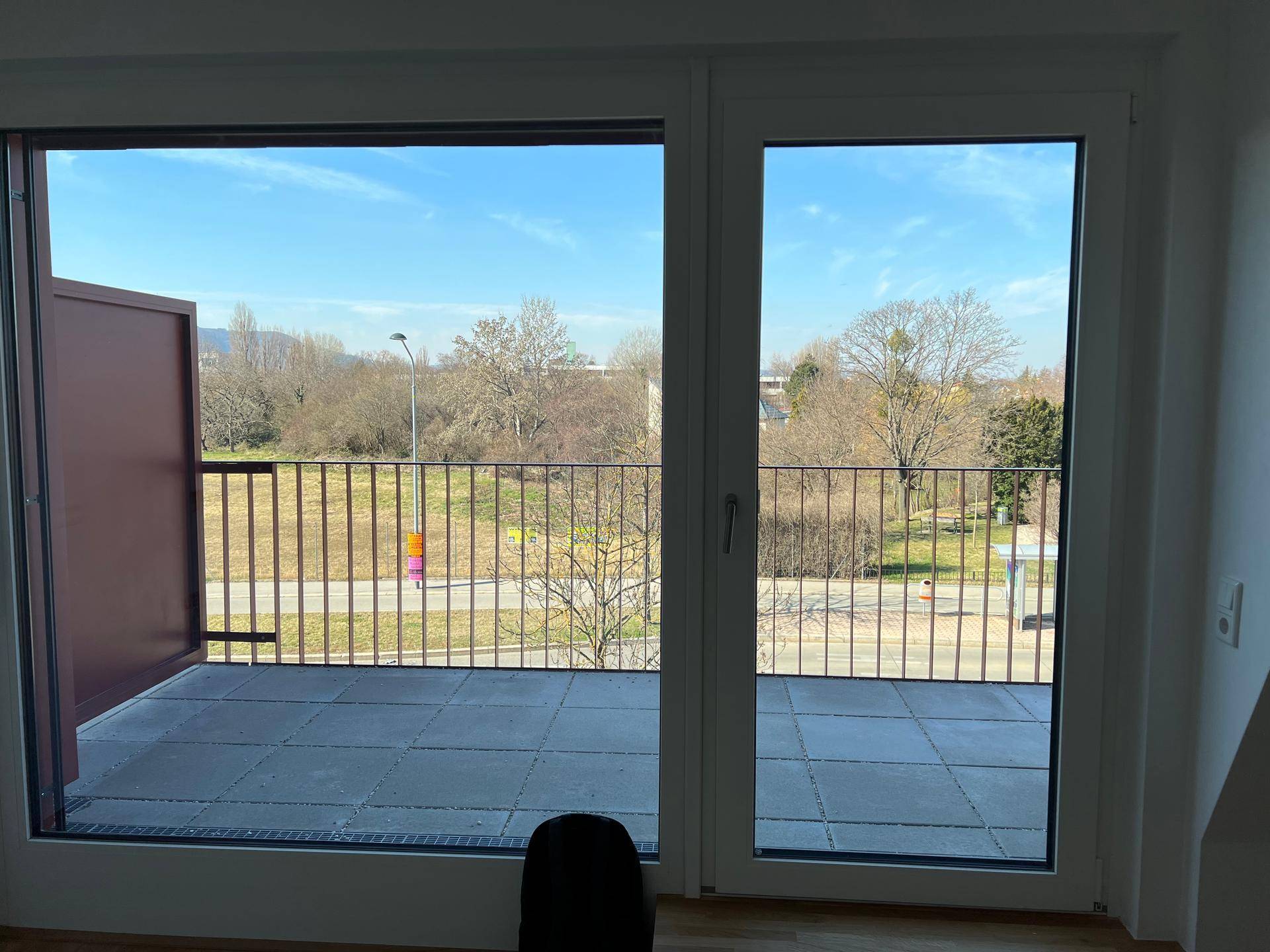 Lichtdurchfluteter Raum mit großem Schiebefenster und Zugang zu einer Terrasse mit Weitblick.
