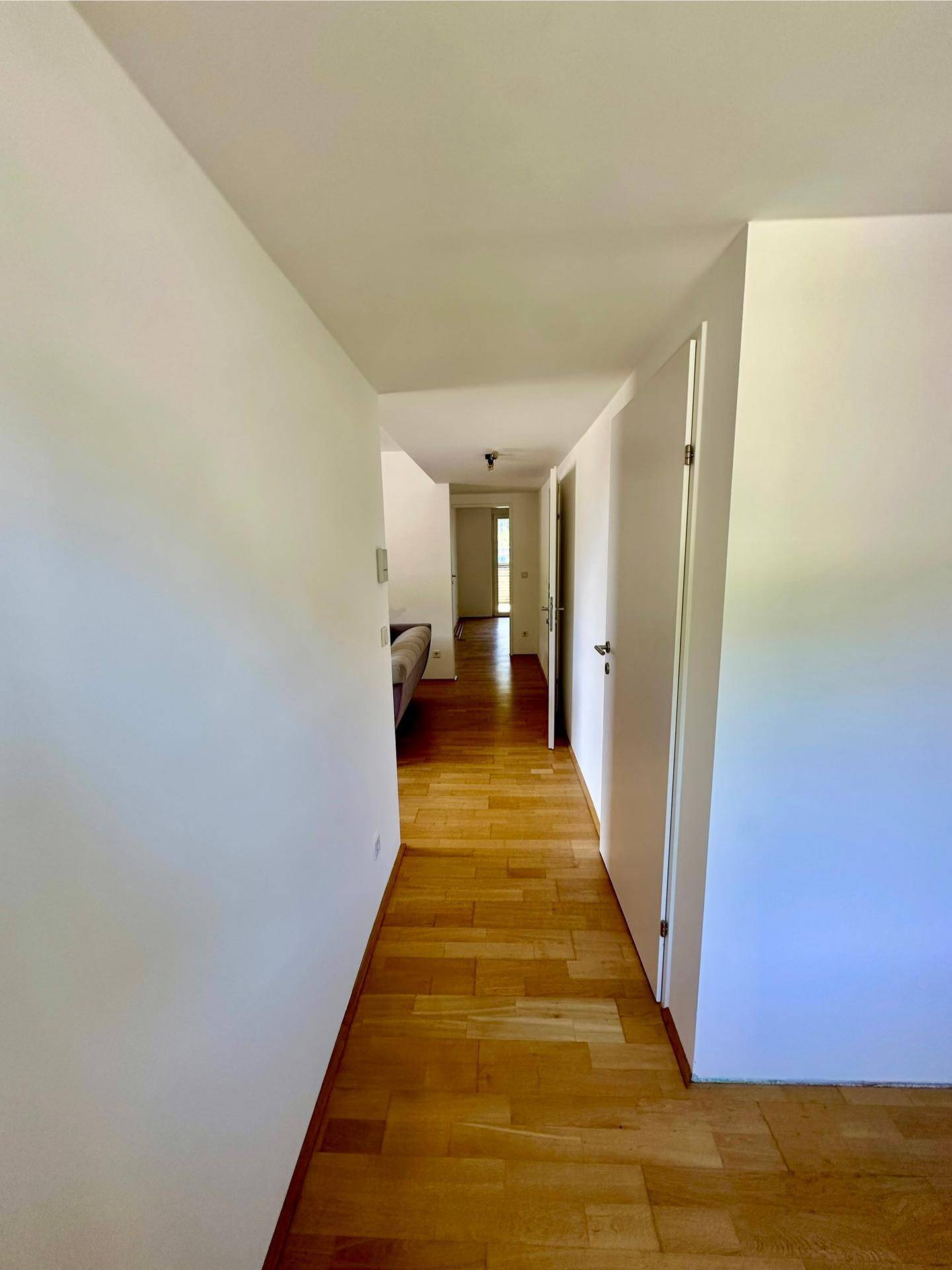 Langer, heller Flur mit Holzboden und mehreren Türen, der die verschiedenen Wohnbereiche verbindet.