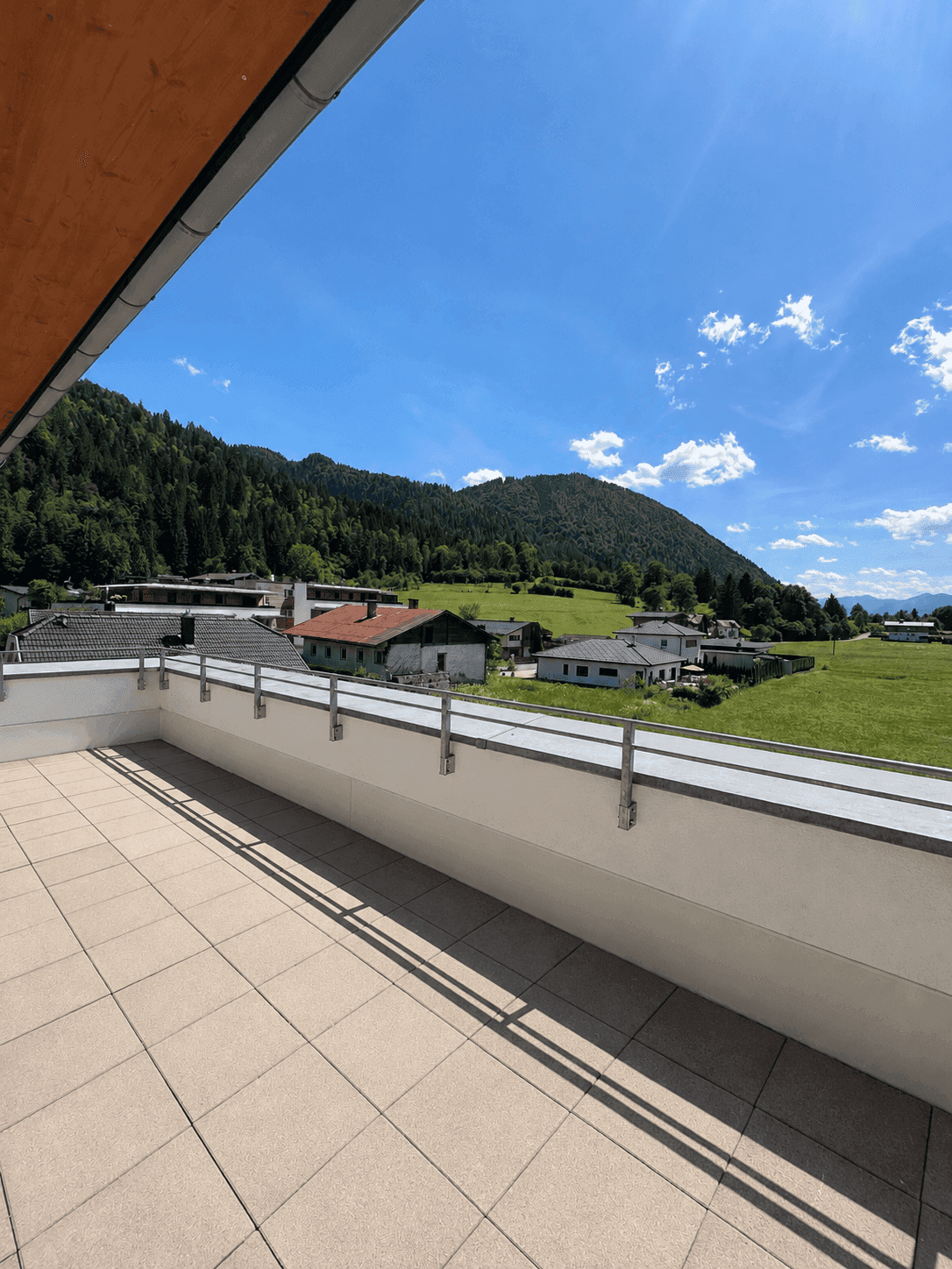 Geräumige Terrasse mit Fliesenboden und weitem Blick auf die umliegende Berglandschaft.