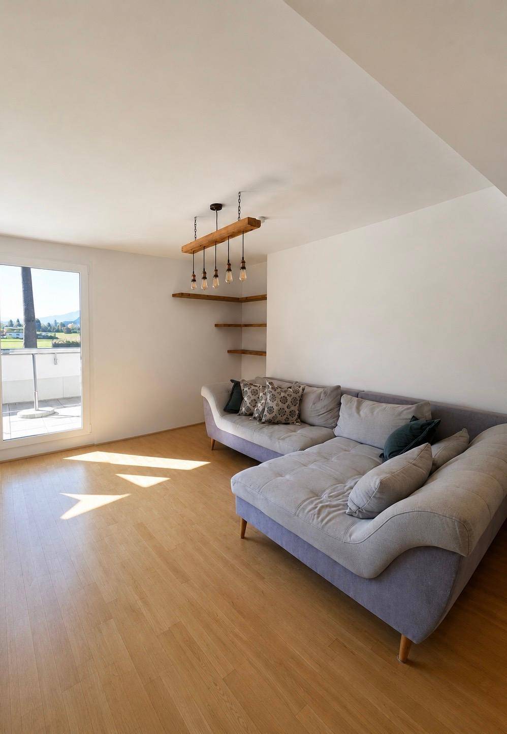 Heller Wohnbereich mit bequemer Couch, Holzboden und Zugang zur sonnigen Terrasse.