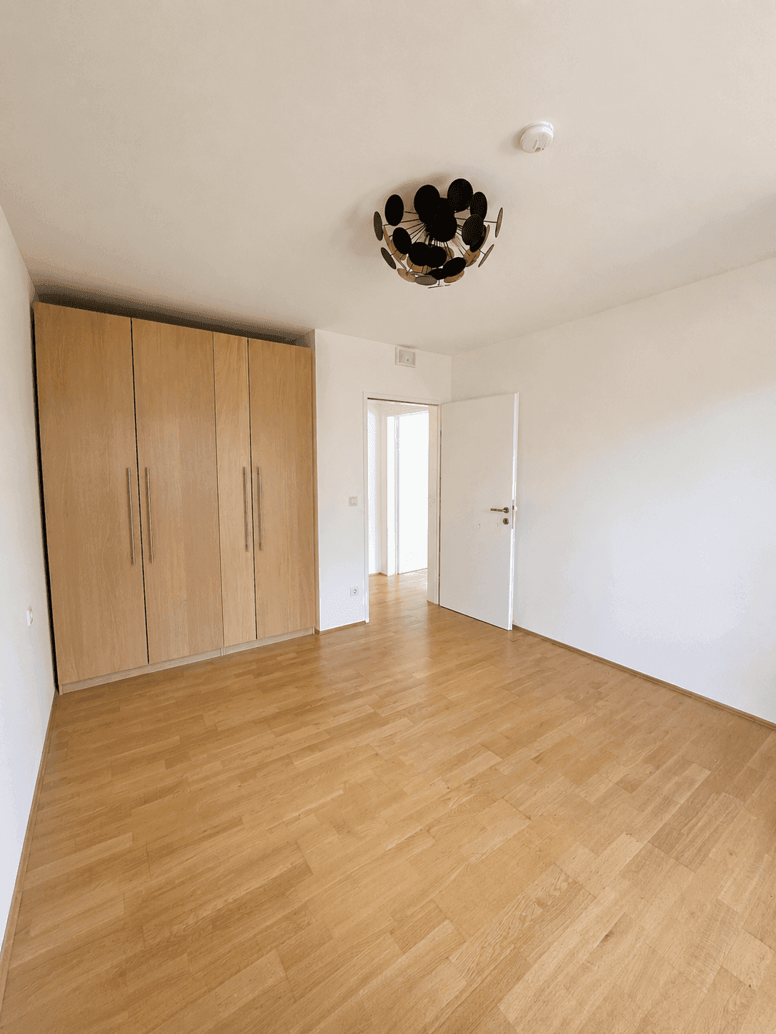 Helles Schlafzimmer mit Holzboden und großem Einbauschrank, bereit zur individuellen Gestaltung.